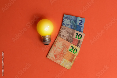 Brazilian Money and lamp isolated on orange background.