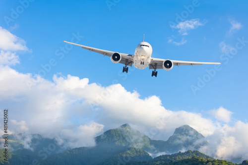 Airplane is flying over low mountains. Amazing landscape with passenger plane landing in difficult conditions.