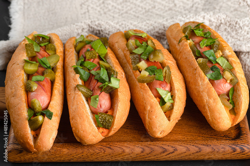 Hot dog, hot dog with pickled cucumbers, jalapeno peppers, carrots, greens on a black background