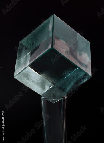 glass cube on a shot glass, on a black background