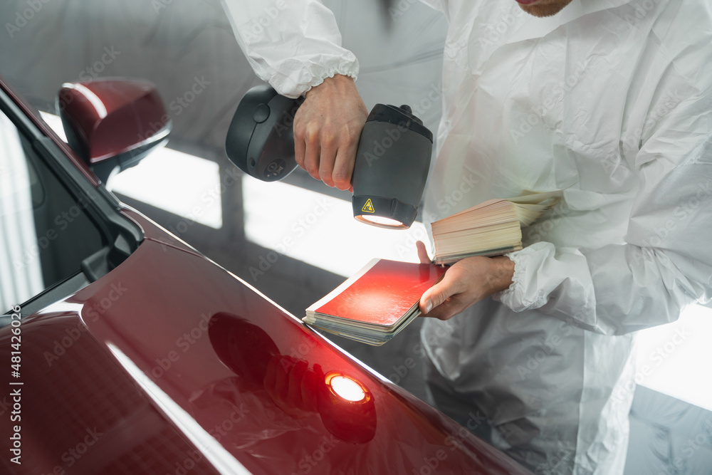 Car painter man determines the correct tone of a vehicle body colour