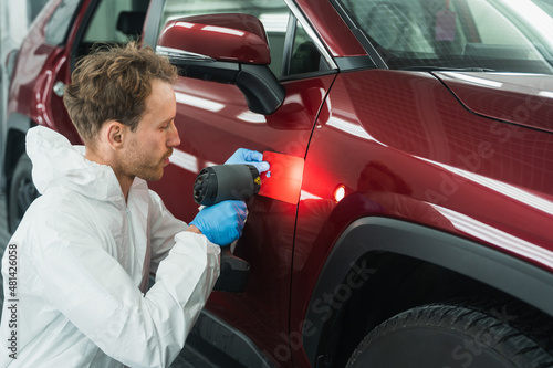 Картината върху платно Professional auto painter matches car paint color with lamp and samples