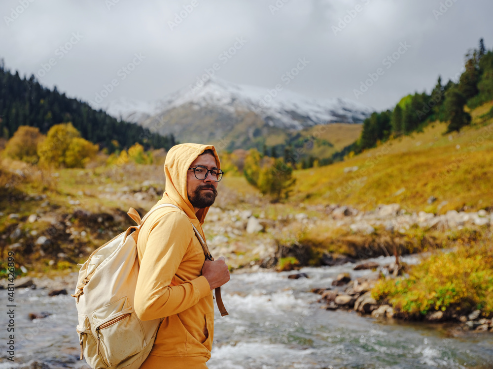Man hikes mountains with travel backpack. Wandering lifestyle, adventure concept autumn vacation outdoors, alone in wild. Travel to North Caucasus, Arkhyz, Russia, road to Dukkinsky lakes
