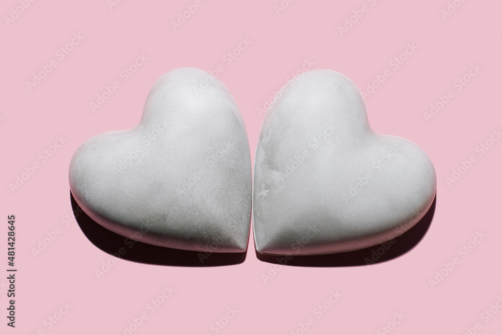 Obraz premium Two concrete/plaster hearts on pastel pink background. Minimalist Valentines Day Concept. Love background.