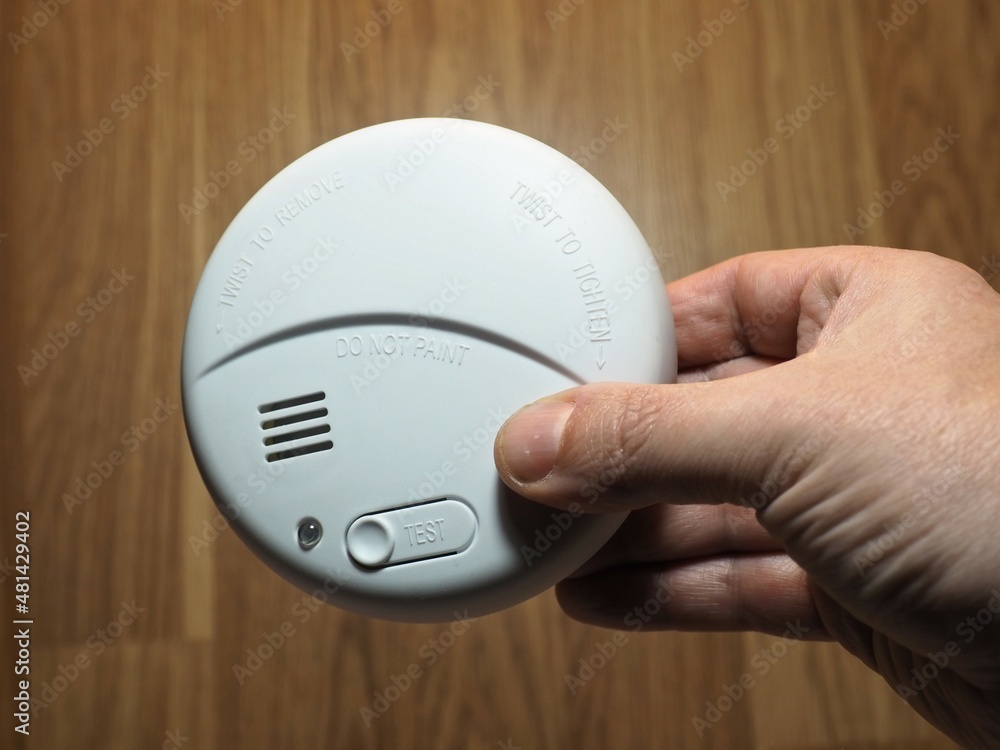 Photoelectric smoke detector. Hand with smoke detector. Residential fire safety devices - obrazy, fototapety, plakaty 