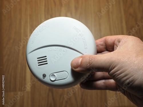 Photoelectric smoke detector. Hand with smoke detector. Residential fire safety devices photo