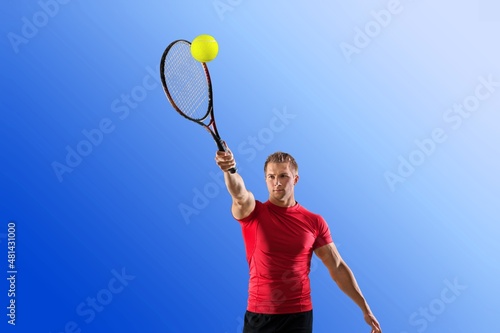 Youyng man Holding A Paddle Tennis Racket Hitting The Ball On A Blue Background. © BillionPhotos.com