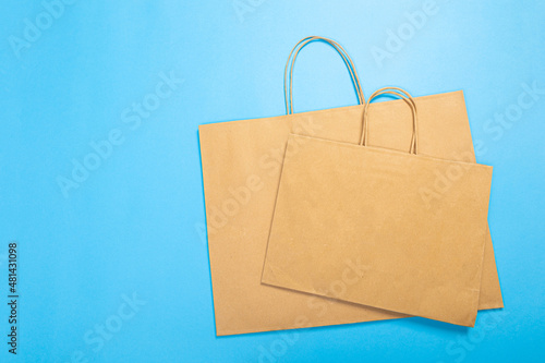 Blank brown paper carrier bag with handles for shopping, facing front on blue background Commercial, sale and advertisement concept.