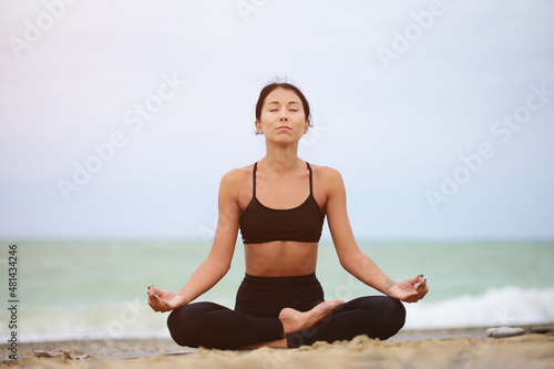 Beautiful portrait of young woman meditating on the seaside. Yoga sport. Healthy wellness lifestyle. Spiritual health. Personal fulfillment.