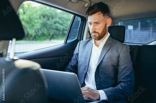 Male businessman working on laptop sitting on passenger seat of car © Liubomir