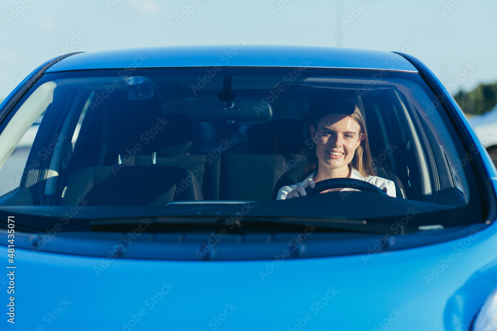 portrait of a successful and happy woman driving a car, photo from the front through the glass portrait of a successful and happy woman driving a car, photo from the front through the glass
