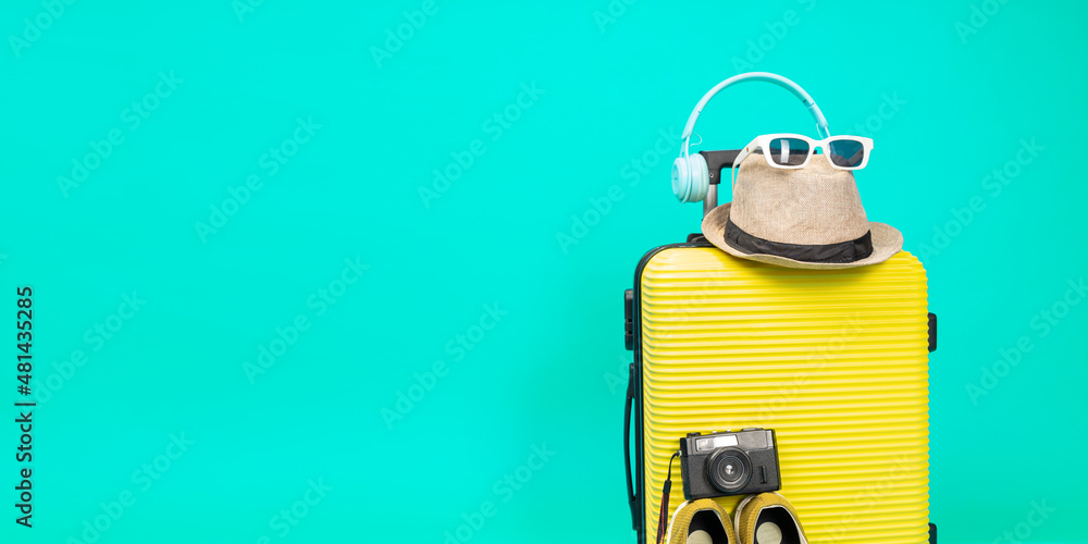 Yellow suitcase with sun glasses, hat and camera on pastel blue background. travel concept. minimal style Yellow suitcase with sun glasses, hat and camera on pastel blue background. travel concept. minimal style