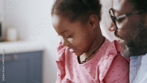 Smiling African parents talking something to their daughter at home