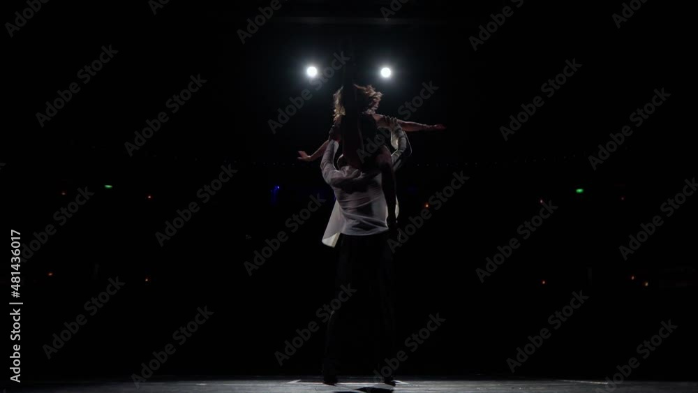 Woman runs somersault,man lifts her in support on outstretched arms back to back up on his shoulders,makes several turns,faces camera,girl slides down,they stand arms crossed.Dancers couple on stage. Woman runs somersault,man lifts her in support on outstretched arms back to back up on his shoulders,makes several turns,faces camera,girl slides down,they stand arms crossed.Dancers couple on stage.
