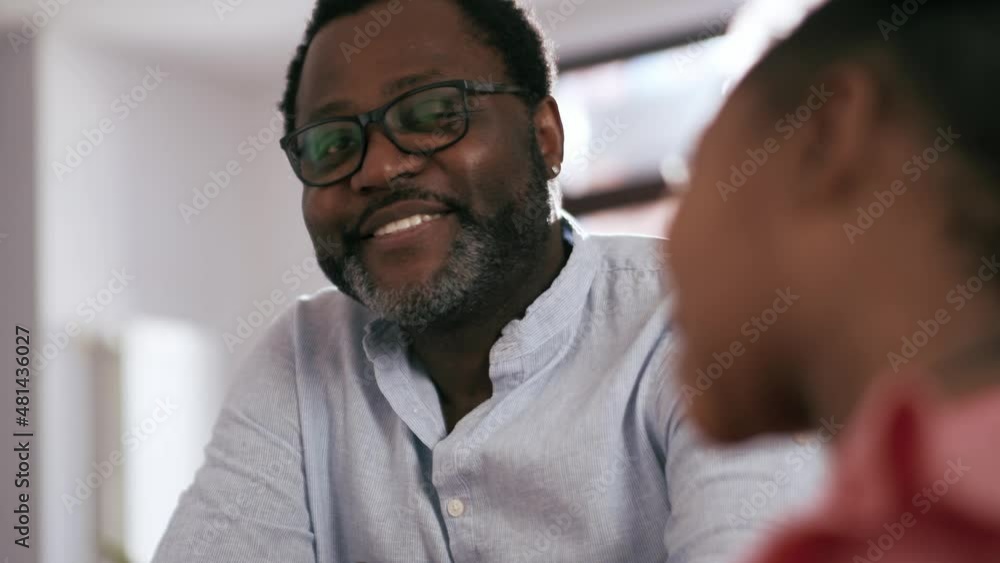 Cheerful African man with eyeglasses talking and looking at his daughter at home Cheerful African man with eyeglasses talking and looking at his daughter at home