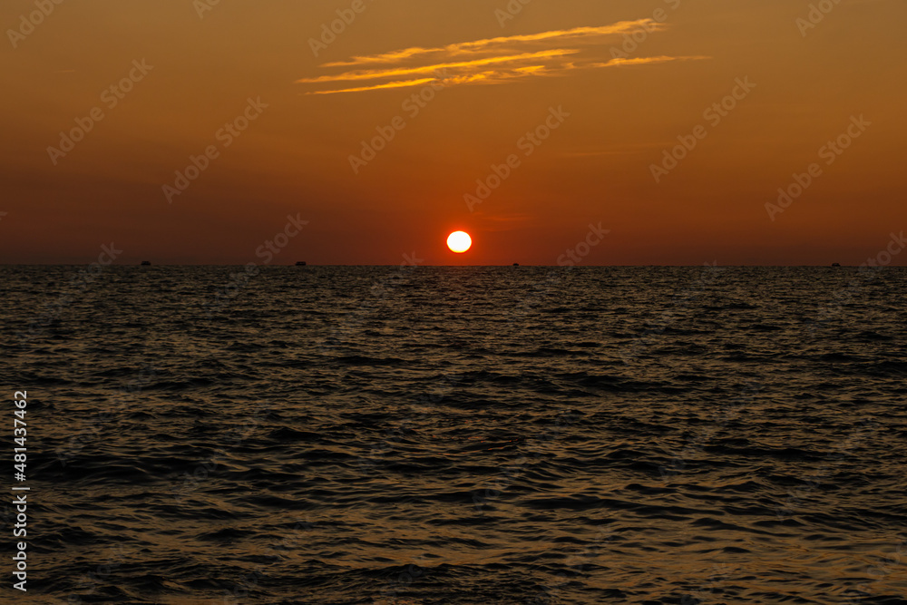 Beautiful orange sunrise is on the beach by the sea with black ship silhouettes
