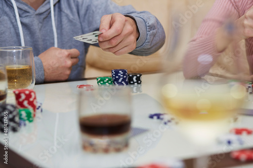 Player of poker game on the table with chips and cards. Glasses of whiskey and champagne. Gambling concept. Candid moment.. Selective focus