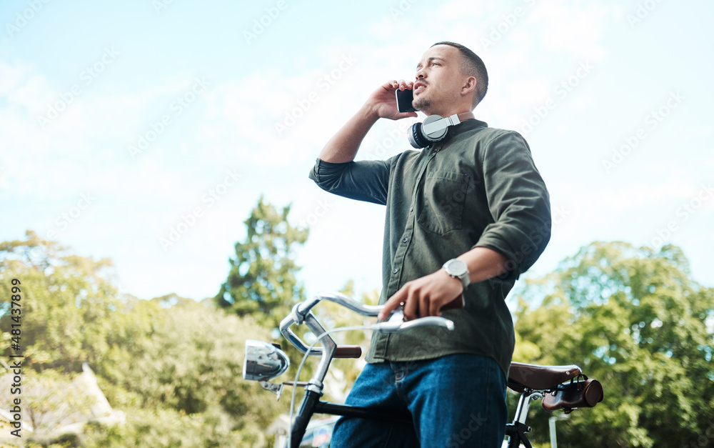 There's power in perseverance. Shot of a young businessman using a smartphone while riding his bicycle in the city. There's power in perseverance. Shot of a young businessman using a smartphone while riding his bicycle in the city.