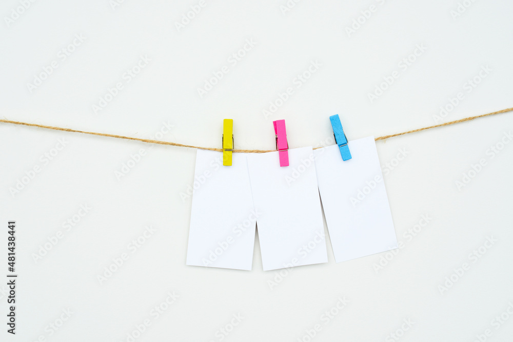three empty white cards hang on colour clothespins, space for text, tags, word three-letters, mock-up three empty white cards hang on colour clothespins, space for text, tags, word three-letters, mock-up
