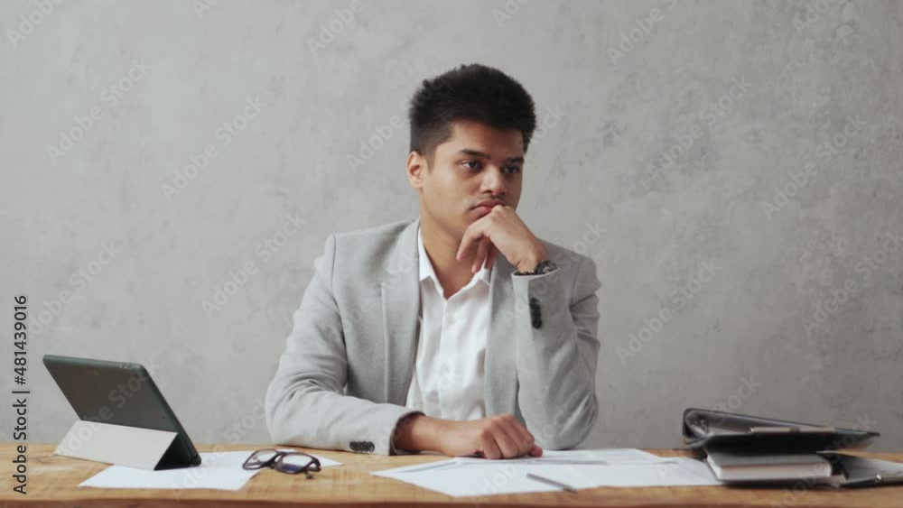 Pensive Indian businessman thinking about something in office Pensive Indian businessman thinking about something in office