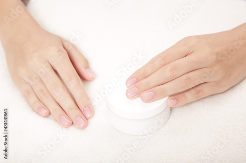 woman hands open a jar of cream. skin care concept. Gray background