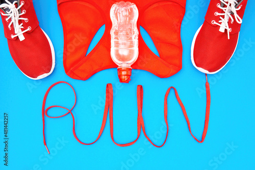 Running shoes and a tank with the lettering RUN made from a shoelace on a blue background. Creative active lifestyle concept.