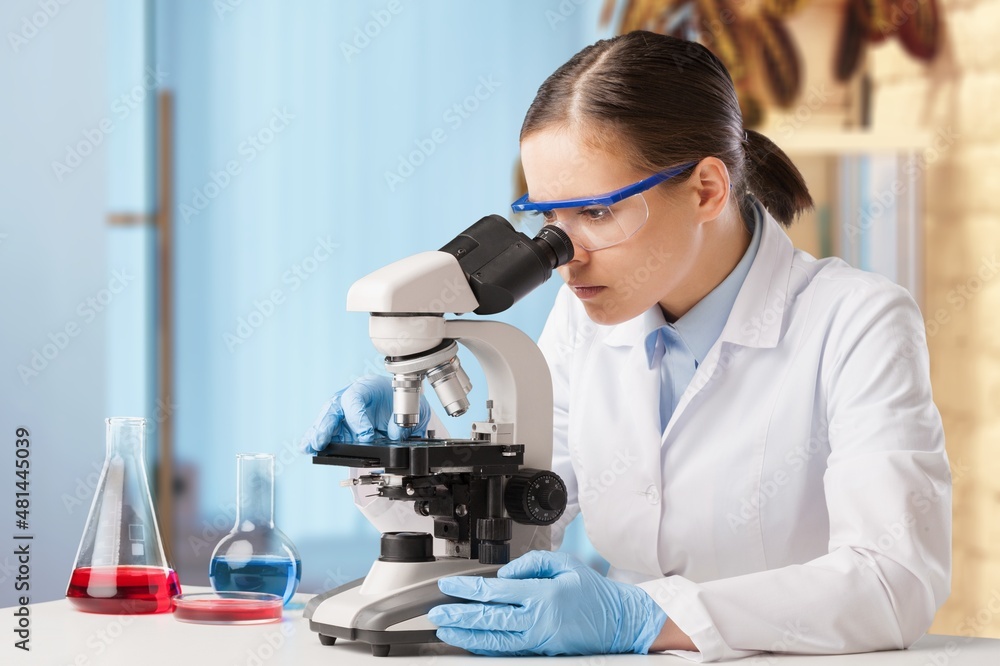 Microbiologist examining biological samples with a microscope in the laboratory. Microbiologist examining biological samples with a microscope in the laboratory.