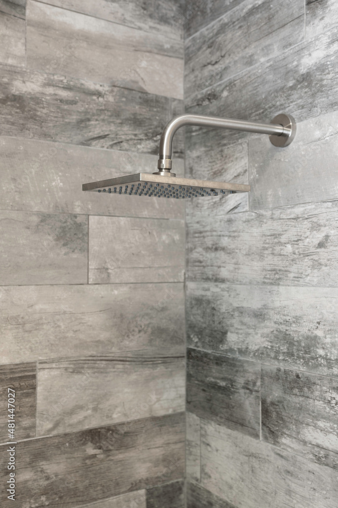 Detail of modern chrome shower head with faux wood tile. Detail of modern chrome shower head with faux wood tile.
