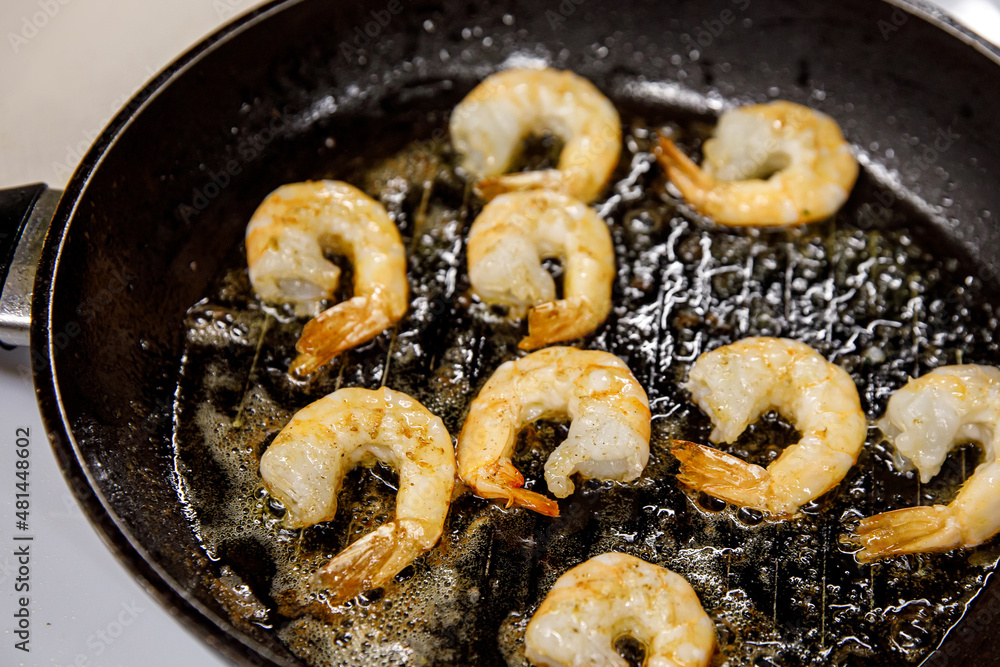 Fried shrimp on pan, preparing dish with seafood.