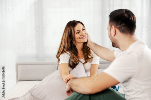 A man cuddling his wife in the bed in the morning at their apartment.