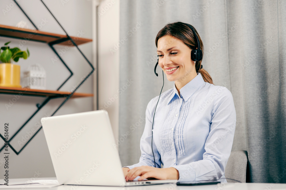 A happy female technical support operator working form home on her laptop. A happy female technical support operator working form home on her laptop.