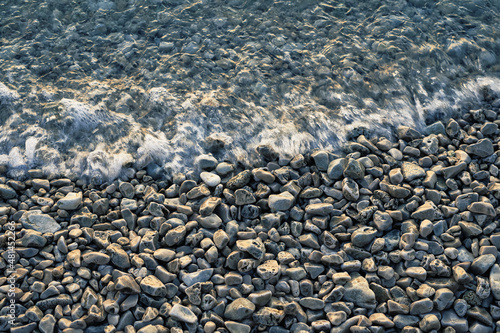 Pebble stones by the sea. Silky waves of sea.