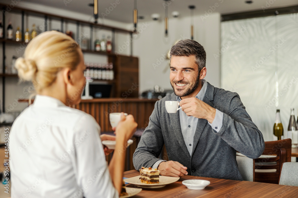 The sophisticated couple is sitting in the restaurant, drinking coffee and having a cake for dessert. Couple drinking coffee The sophisticated couple is sitting in the restaurant, drinking coffee and having a cake for dessert. Couple drinking coffee
