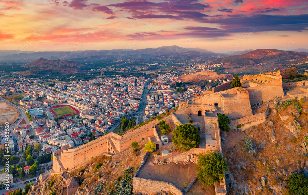 Beautiful summer view from flying drone of fortress of Palamidi. Splendid evening view of Peloponnese peninsula, Greece, Europe. Sunset on Nafplion town. Traveling concept background.