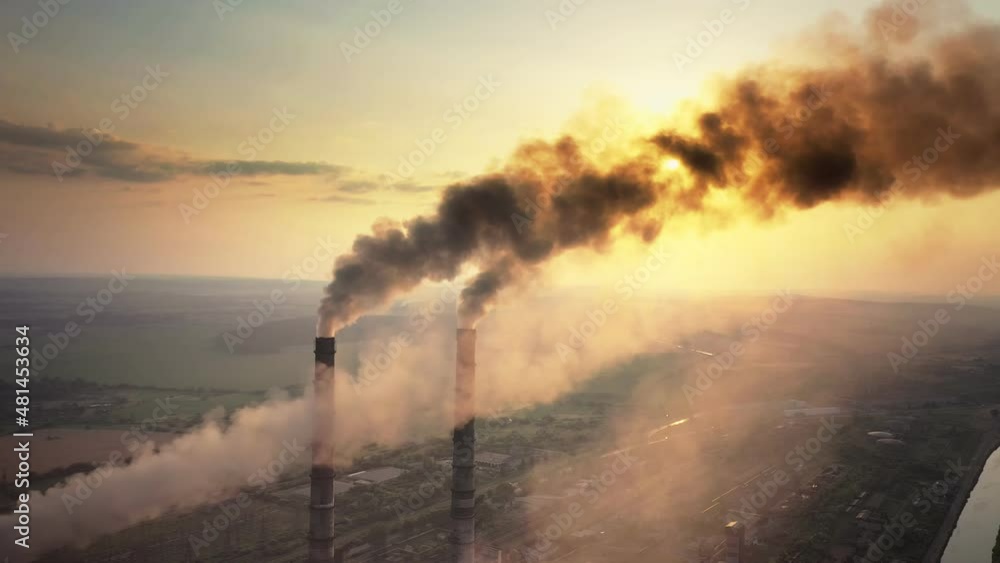 Aerial view of coal power plant high pipes with black smoke moving up polluting atmosphere at sunset Aerial view of coal power plant high pipes with black smoke moving up polluting atmosphere at sunset