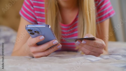 Young woman paying with credit card online. Home shopping with mobile phone. White female buying in web store with modern smartphone and internet connection. Person making a purchase in mobile app photo