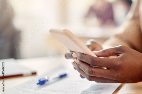 Close-up of black female student uses smart phone in the classroom.