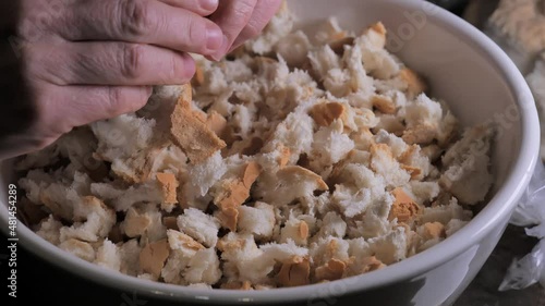 Woman's hands cutting traditional bread with her fingers, close-up in 4K. Container with village bread