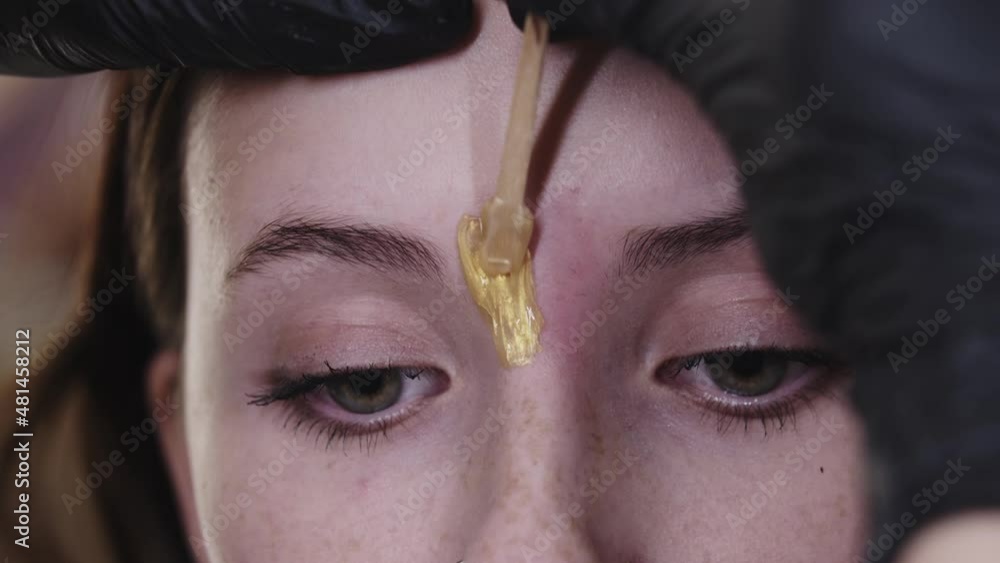 Applying wax on the small little hairs in between the eyebrows of
