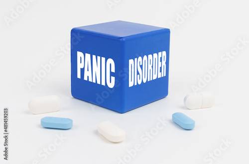 On a white surface are pills and a blue cube that says - Panic Disorder