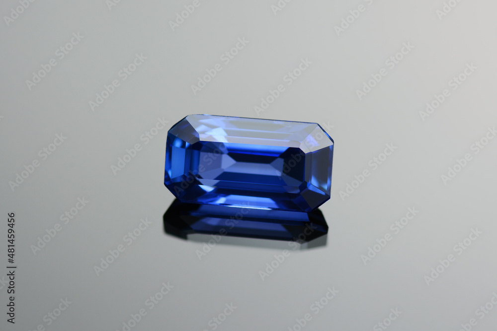 Ceylon blue sapphire gemstone. Natural precious stone setting rich cornflower blue color. Genuine 1 class sapphire stone, emerald cut, gentle heat. Clean, deep saturated. Gray gradient background. Ceylon blue sapphire gemstone. Natural precious stone setting rich cornflower blue color. Genuine 1 class sapphire stone, emerald cut, gentle heat. Clean, deep saturated. Gray gradient background.