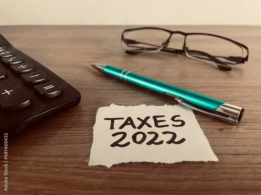 Φωτογραφία Taxes 2022 text with pen, calculator and glasses on office desk, business and fi