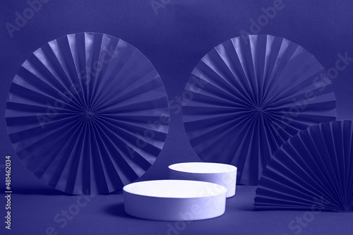 White podium or pedestal with decorative red paper fans on a very peri background. Product presentation concept. copy space