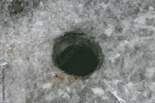Winter hole in the ice of the lake. Winter fishing. Close-up.