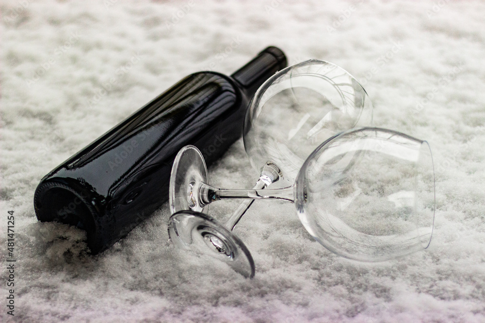 Bottle of wine without a label with empty glasses on the snow