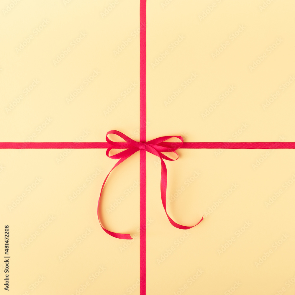 Minimal creative idea of gift box made of pink ribbon with bow isolated on yellow pastel background. Valentines day, birthday, bff or annivesary concept. Minimal creative idea of gift box made of pink ribbon with bow isolated on yellow pastel background. Valentines day, birthday, bff or annivesary concept.