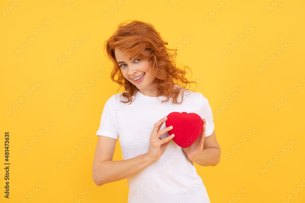 cheerful redhead woman hold love heart on yellow background, donation cheerful redhead woman hold love heart on yellow background, donation