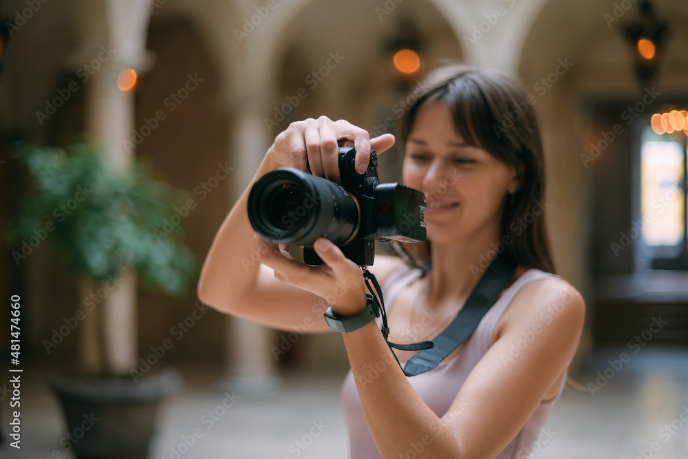 Portrait of a tourist girl with a camera in her hands in the hall of the museum. Young beautiful woman takes pictures on excursions Portrait of a tourist girl with a camera in her hands in the hall of the museum. Young beautiful woman takes pictures on excursions
