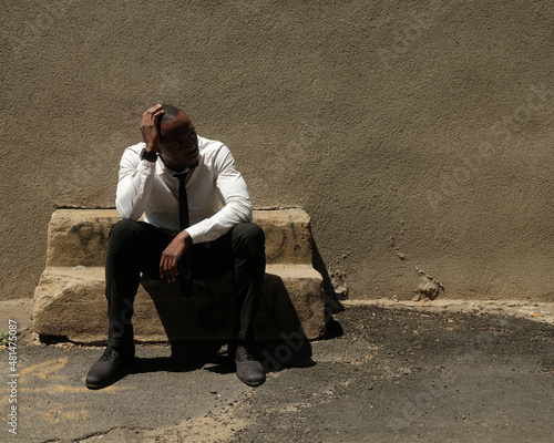 USA, New York City, Tired businessman sitting on old stone bench outdoors