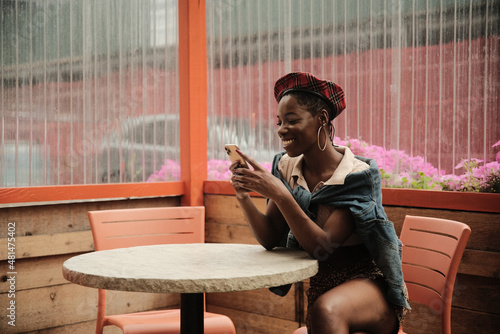 USA, New York, Stylish woman looking at smart phone at sidewalk cafe table